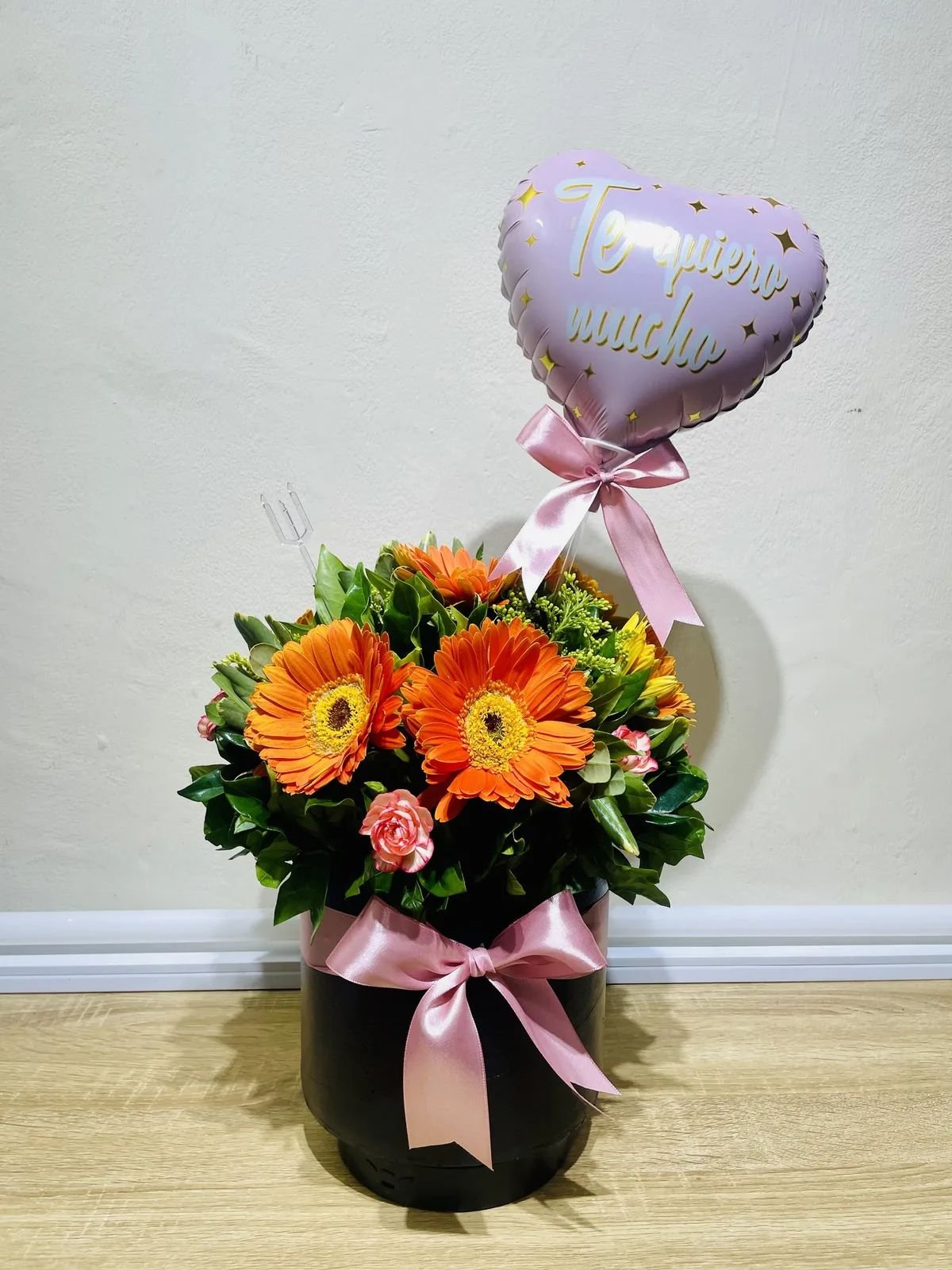 Arreglo de gerberas naranjas en caja negra con un globo.